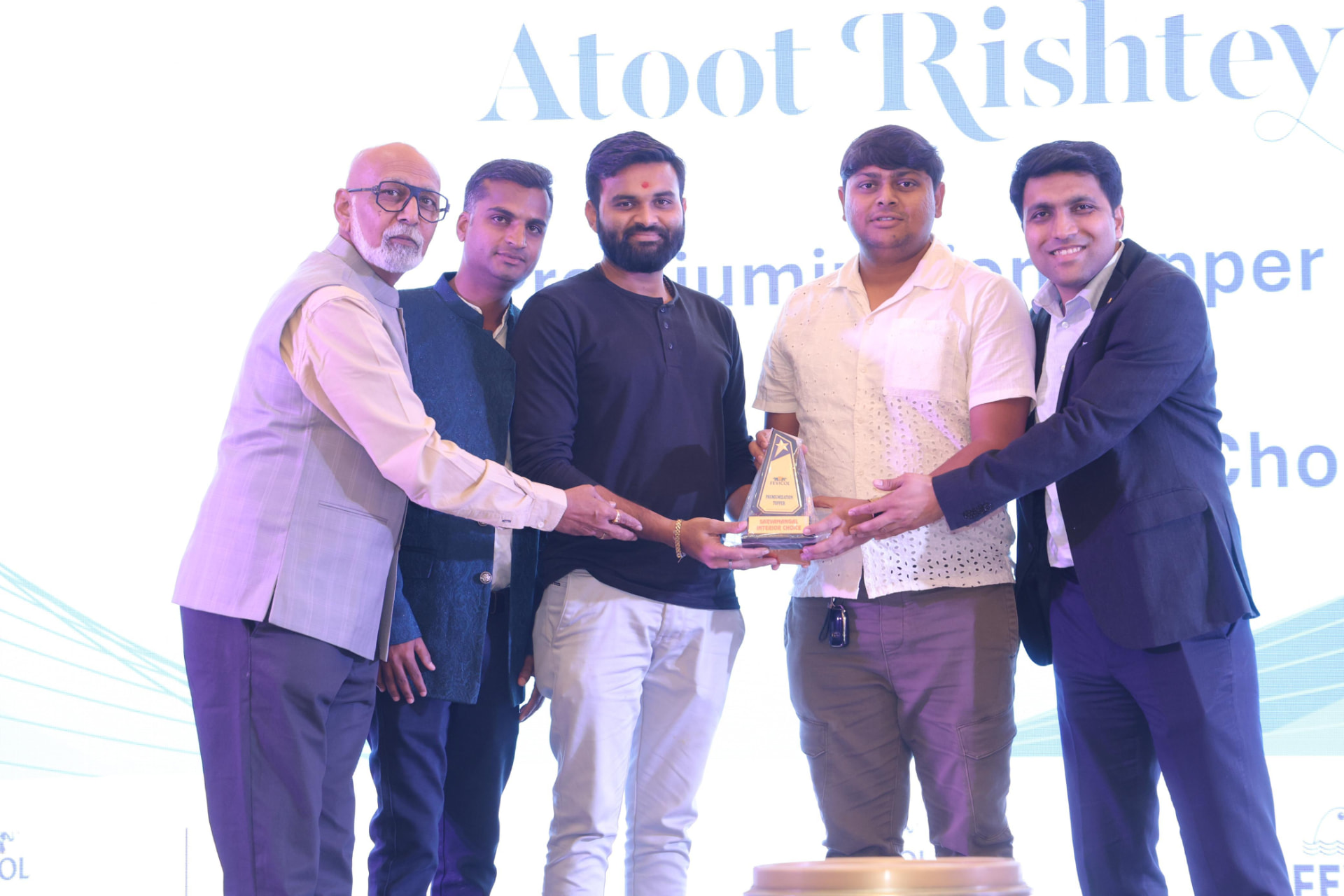 Five people presenting an award trophy at the Atoot Rishtey recognition event